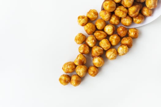 Scattered hazelnuts in caramel on a white background. Very tasty and healthy and high-calorie dessert