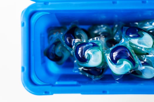 Washing powders in multi-colored capsules are in a blue plastic box. The concept of washing and cleanliness