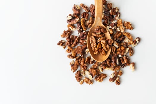 Walnuts in a wooden spoon scattered on a white table. Close-up, noise, graininess, selective focus