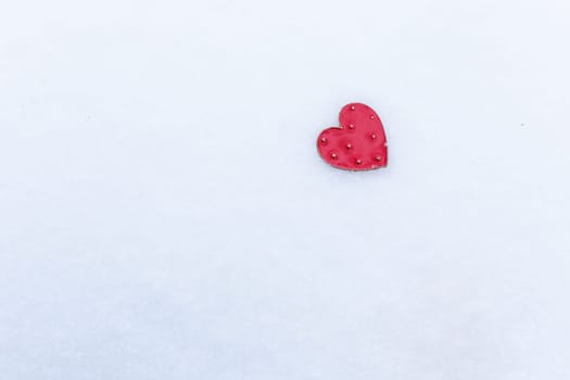 Red heart lies in the snow, Valentine's Day holiday concept, space for an inscription