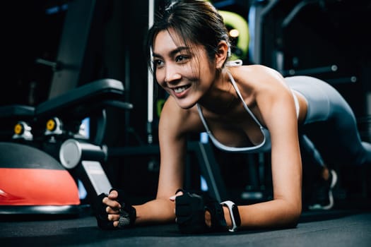 Fit young woman maintaining a plank position on a stability ball to improve core strength and balance during her indoor gym workout, exercise in dark gym background