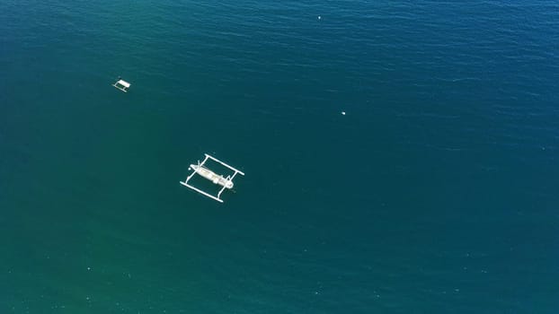 Aerial view of a peaceful Cemare beach in Lombok, Indonesia. Clear blue water, traditional fishing boats, and a sandy shoreline create a picturesque scene.