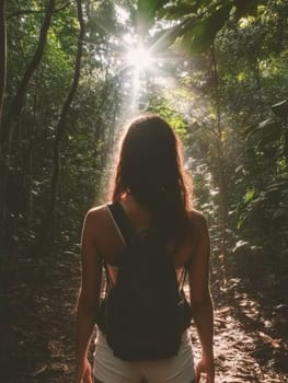 Silhouette of a hiker with backpack standing on a forest trail, bathed in sunlight streaming through lush tropical foliage.