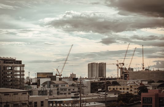 Bangkok, Thailand - Aug 14, 2024 - View of Construction of tall buildings with a crane and background of Dramatic sky in the city of Bangkok. Tower crane, Construction cranes, Construction and urban development. use it as your Wallpaper, Poster and Space for text, Selective focus.