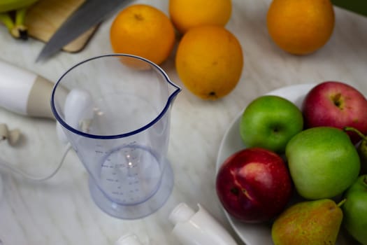 Measuring cup for making sports fruit cocktail on the table. Bowl for chopping fruits with blender when preparing healthy drink with vitamins for immunity