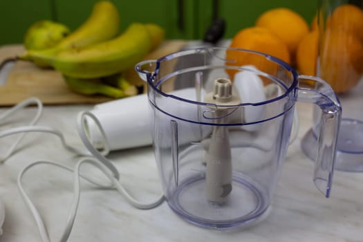 Container with blades and blender on background of fruits for chopping and making healthy drink