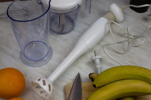 Blender on table with containers for grinding and fruits for making smoothies. Ingredients for healthy drink with vitamins for strengthening human health