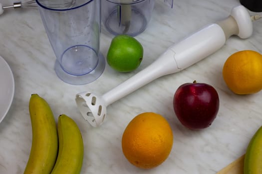 Blender lies on the table next to fruits. Ingredients for grinding in a blender. Fresh fruits for creating a sports drink for people health