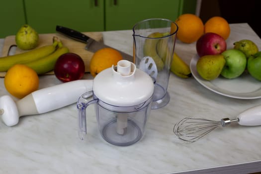 Table with blender and fruits in home kitchen for making sports drink to boost vitamins. Healthy fruits for human health, making smoothies at home