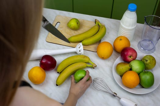 Girl takes apple on table to grind in blender and make sports cocktail with vitamins. Healthy drink for sporty lifestyle. Making smoothies and healthy cocktails concept