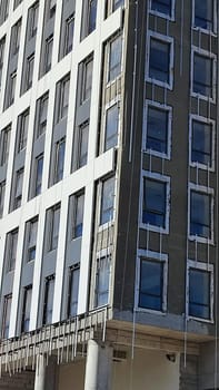 construction of a high-rise gray building, windows office building, city object, blue sky . High quality photo