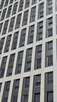 construction of a high-rise gray building, windows office building, city object, blue sky . High quality photo