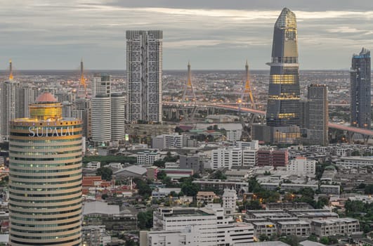 Bangkok, Thailand - 29 Aug, 2024 - Aerial view of KingBridge tower, Supalai Grand Tower alongside the iconic landmark of Bhumibol Bridge, Stunning At skyline of bangkok business district with Skyscrapers use it as your wallpaper, poster and banner design, Selective focus.