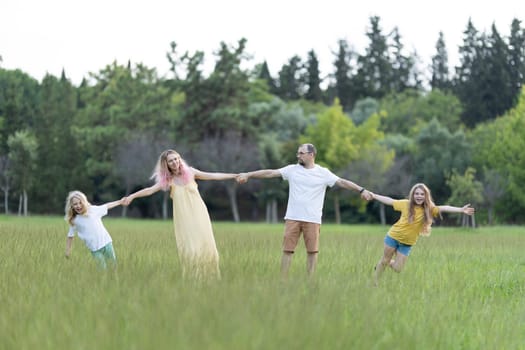Happy family holding hands and spinning in a park, enjoying their time together
