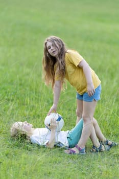 Two sisters are enjoying a beautiful summer day playing with a soccer ball in a field