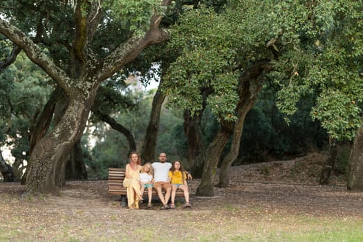 Family is enjoying a relaxing day outdoors sitting on a park bench