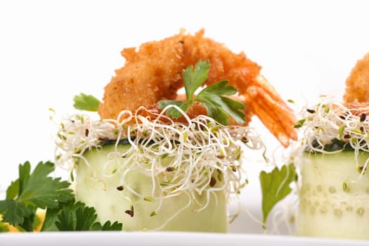 Cucumber appetizer with fried breaded shrimp on a bed of microgreens