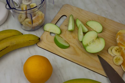 Cutting board with fruits with blender for making sports cocktail. Table with ingredients for fruit smoothie with vitamins at home. Healthy food and lifestyle concept