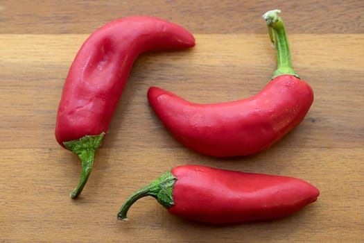 Overhead view of whole red peppers on a cutting board.