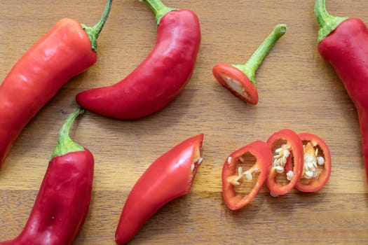 Overhead view of whole and sliced red peppers on a cutting board.
