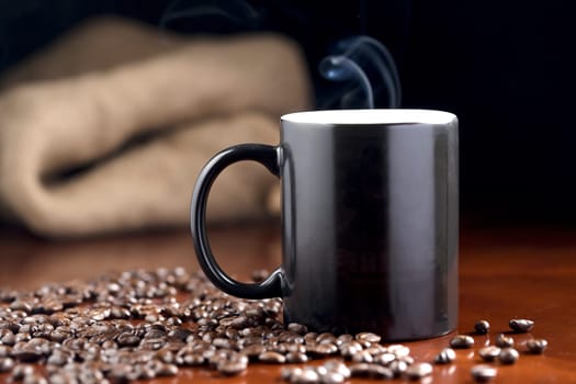A studio photo of steaming coffee in a cup and coffee beans.