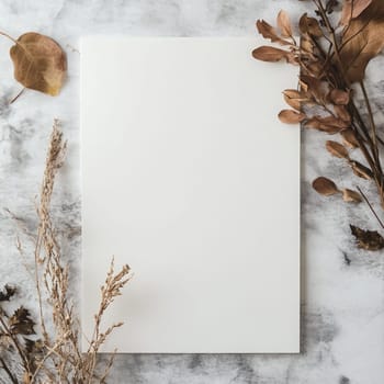 A piece of blank paper lies on a textured fabric backdrop surrounded by delicate dried flowers, creating an inviting space for writing or artistic projects.