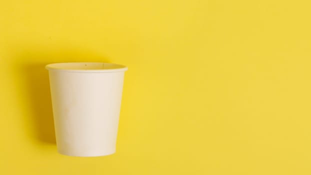 The concept of environmental protection. Copy the space. Disposable paper cup for coffee and tea on a yellow-orange background. coffee break...