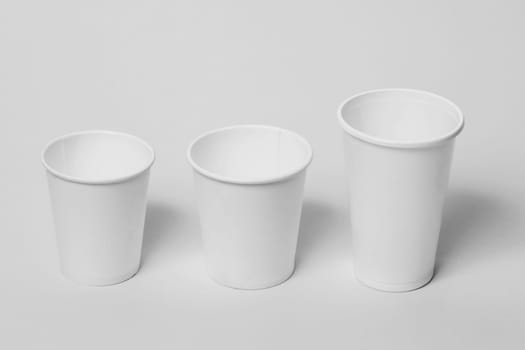 Three white paper disposable cups on a white background.