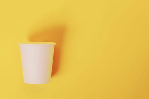 Disposable paper cup for coffee and tea on a yellow-orange background. coffee break. ecological concept...