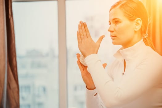 Athletic slim caucasian woman doing thigh self-massage with a massage ball indoors. Self-isolating massage.