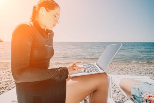 Digital nomad, Business man working on laptop by the sea. Man typing on computer by the sea at sunset, makes a business transaction online from a distance. Freelance, remote work on vacation