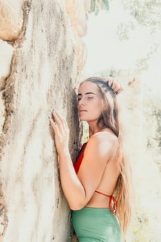 Woman travel sea. Young Happy woman in a long red dress posing on a beach near the sea on background of volcanic rocks, like in Iceland, sharing travel adventure journey