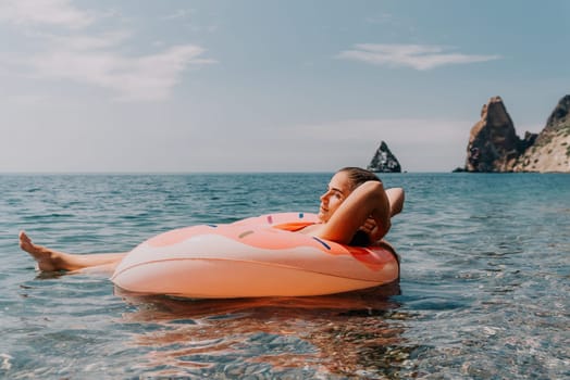 Summer Vacation Woman in hat floats on an inflatable donut mattress, a water toy swim ring. Unrecognizable young woman relaxing and enjoying family summer travel holidays vacation on the sea