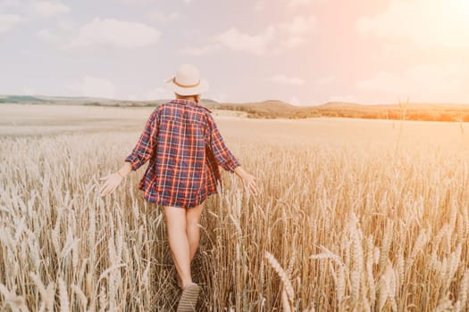 Woman farmer walks through a wheat field at sunset, touching green ears of wheat with his hands. Hand farmer is touching ears of wheat on field in sun, inspecting her harvest. Agricultural business.