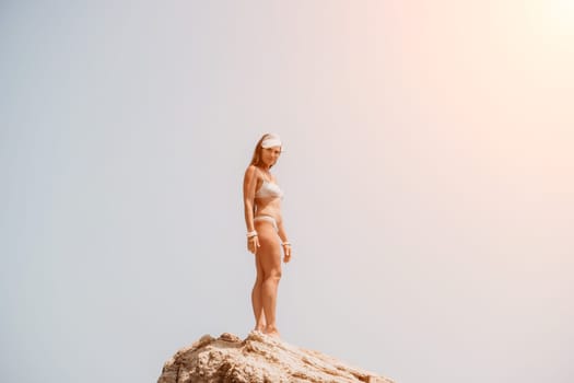 Woman meditating in yoga pose silhouette at the ocean, beach and rock mountains. Motivation and inspirational fit and exercising. Healthy lifestyle outdoors in nature, fitness concept.