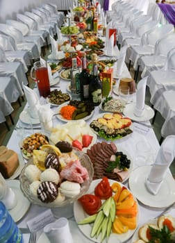 Richly decorated and served tables with food for a wedding banquet.