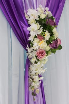 Backdrop curtain decoration. Multi-colored bouquet on a lilac and white curtain. Wedding decoration with flowers.