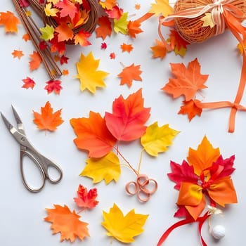 A crafting table is adorned with vibrant paper leaves in shades of yellow, orange, and red, alongside scissors, twine, and ribbons set for creating autumn-themed decorations.