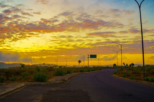 A breathtaking sunset paints the sky in vibrant hues of orange and pink, casting a warm glow over a vast landscape near Mandalika.
