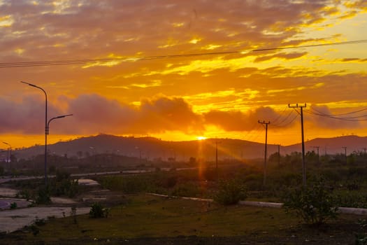 A breathtaking sunset paints the sky in vibrant hues of orange and pink, casting a warm glow over a vast landscape near Mandalika.