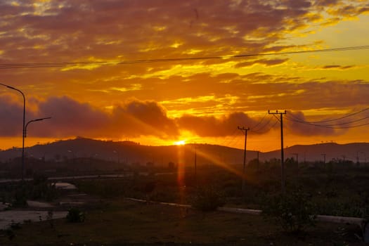A breathtaking sunset paints the sky in vibrant hues of orange and pink, casting a warm glow over a vast landscape near Mandalika.