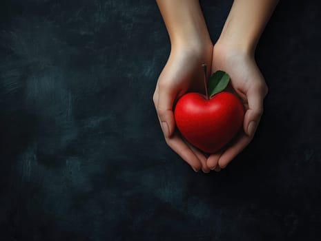 Giving tuesday concept with heart-shaped apple in hands on dark background.