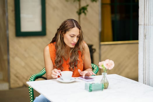 Latin beauty woman enjoying morning coffee using phone in a pavement cafe