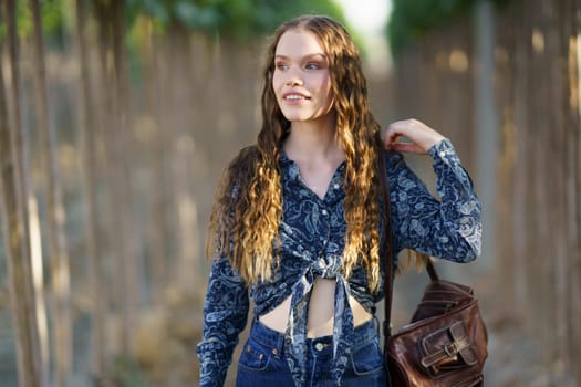 On this sunny day, a young woman with long hair enjoys a serene setting, dressed in a stylish outfit that reflects her cheerful demeanor and passion for beauty, making the moment delightful