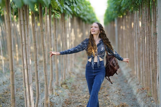 A joyful young woman with long hair strolls through a picturesque grove, savoring natures beauty and fresh air, radiating happiness and freedom, embracing the moment with delight