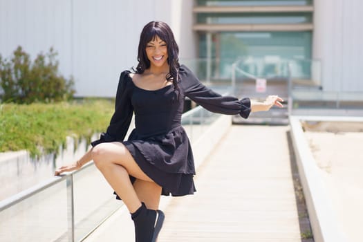 Sensual caucasian young woman smiling while dancing in an urban space under the sun