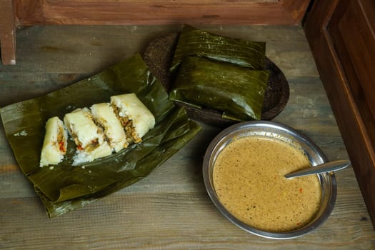 Lontong oncom, a traditional Indonesian dish with steamed rice cakes wrapped in banana leaves, served with spicy peanut sauce.