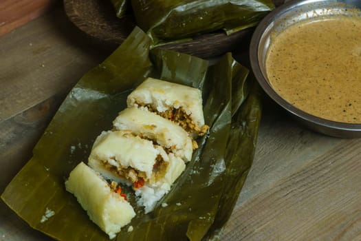 Lontong oncom, a traditional Indonesian dish with steamed rice cakes wrapped in banana leaves, served with spicy peanut sauce.