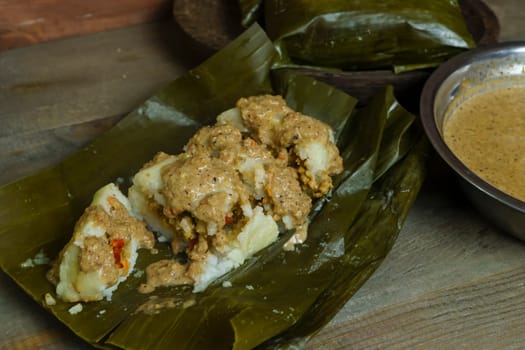 Lontong oncom, a traditional Indonesian dish with steamed rice cakes wrapped in banana leaves, served with spicy peanut sauce.