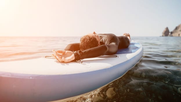 Woman sup yoga. Middle age sporty woman practising yoga pilates on paddle sup surfboard. Female stretching doing workout on sea water. Modern individual hipster outdoor summer sport activity